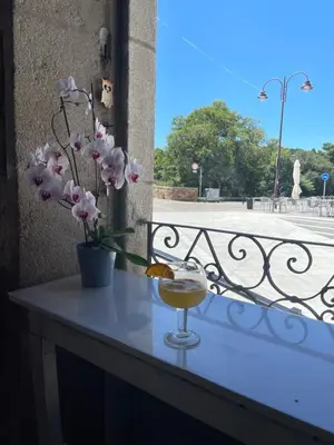 a table with a drink and flowers on a balcony at Roots and Boots in Lugo