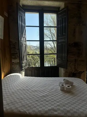 a bedroom with a bed with a large window at Roots and Boots in Lugo