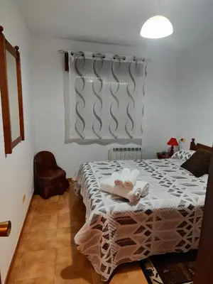 a bedroom with a bed and a chair and a window at Casa Sindo in Teixeira