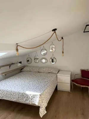 a bedroom with a bed and a red chair at El ático de la terraza in Lugo