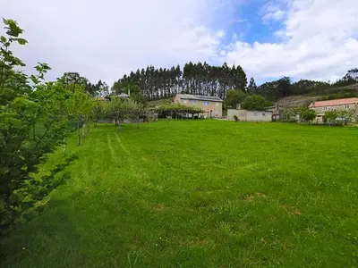 a field of green grass with houses in the background at Casa rural con amplio terreno privado in Irijoa