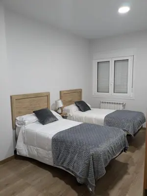 two beds in a room with white walls at Pensión Castineiras in Sarria
