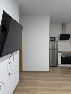 a living room with a tv and a kitchen at Pensión Castineiras in Sarria