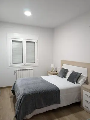a white bedroom with a large bed and a window at Pensión Castineiras in Sarria