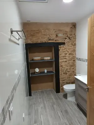 a bathroom with a toilet and a stone wall at Él Rincón de los Sueños B in Vegadecabo