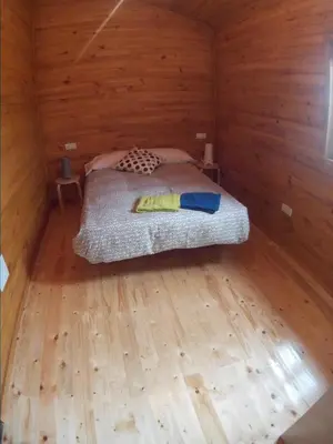 a bedroom with a bed in a wooden cabin at Villas Eldorado-Mascotas Bienvenidas in Barreiros
