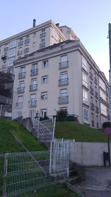 a large white building with stairs in front of it at 2 habitaciones piscina y garage privado in Viveiro
