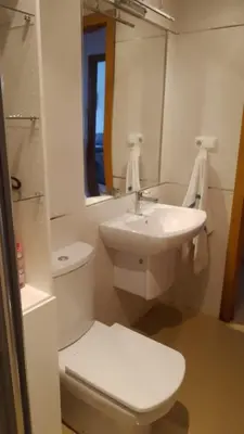 a white bathroom with a toilet and a sink at 2 habitaciones piscina y garage privado in Viveiro