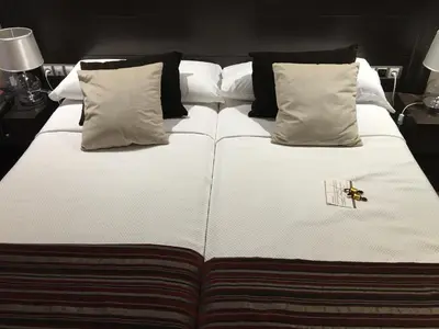 a bed with white sheets and pillows with a bee on it at Hotel Calzada in Arcos