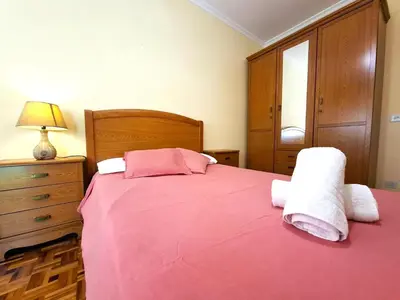 a bedroom with a pink bed with towels on it at Apartamento Playa Foz 4 Dormitorios in Foz