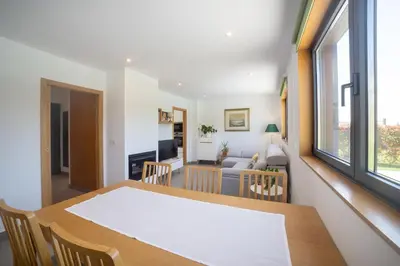 a dining room and living room with a table and chairs at Casa Folgoso in Santiago de Compostela