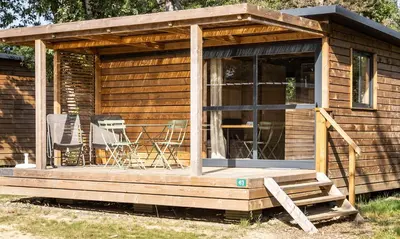 a wooden cabin with two chairs on the porch at Huttopia Caminos de Galicia in Prado