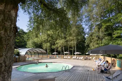a swimming pool with people sitting in chairs around it at Huttopia Caminos de Galicia in Prado