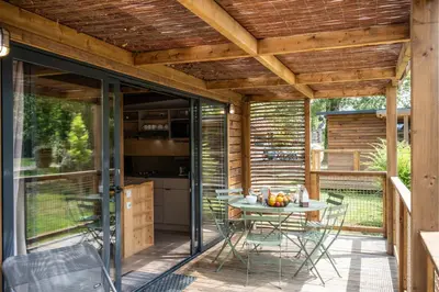 a patio with a table and chairs on a deck at Huttopia Caminos de Galicia in Prado