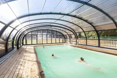 two people swimming in a pool in a building at Huttopia Caminos de Galicia in Prado