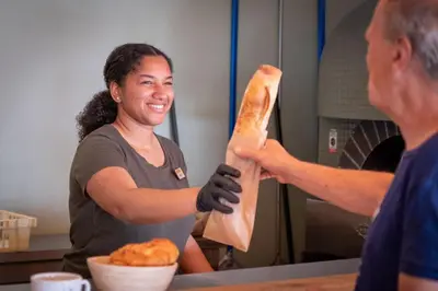 a woman holding a loaf of bread in a kitchen at Huttopia Caminos de Galicia in Prado