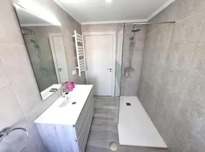 a bathroom with two sinks and a shower and a mirror at Atico Deluxe Limosa romántico moderno junto al mar in San Ciprián
