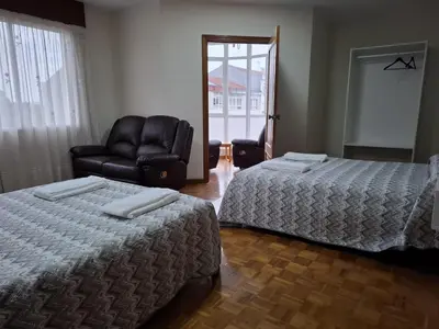 a hotel room with two beds and a leather chair at Road in Palas de Rei