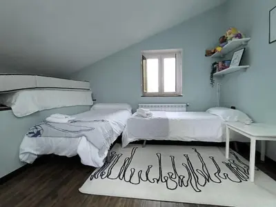 a bedroom with two beds and a table and a window at Relax & Vistas, casa en la roca in Rogüela