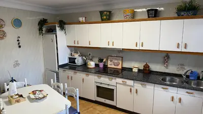 a kitchen with white cabinets and a table and a sink at Piso vacacional en Ribadeo in Ribadeo