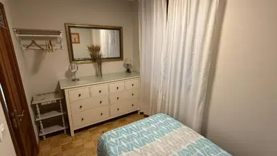 a bedroom with a dresser with a mirror and a bed at Piso vacacional en Ribadeo in Ribadeo