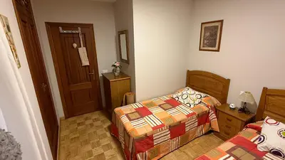a small bedroom with two beds and a door at Piso vacacional en Ribadeo in Ribadeo