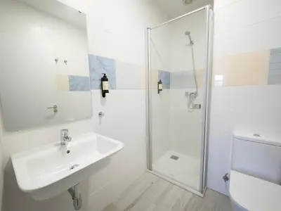 a white bathroom with a sink and a shower at Pensión Spa Cruceiro de Pedrouzo in O Pedrouzo