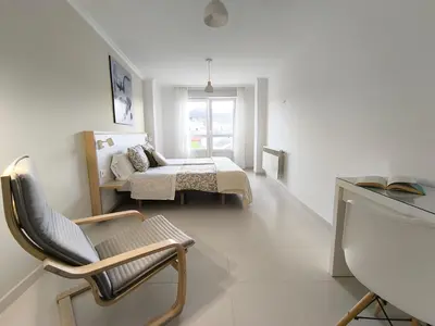 a bedroom with a bed and a chair and a window at Xabarin Apart II in Abadín