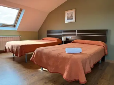 a room with two beds with orange sheets and a window at Pensión Restaurante Tino in Germade