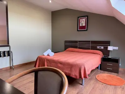 a bedroom with a bed with a red bedspread at Pensión Restaurante Tino in Germade