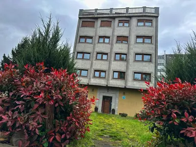 a tall building with red flowers in front of it at Pensión Río Sarria in Sarria
