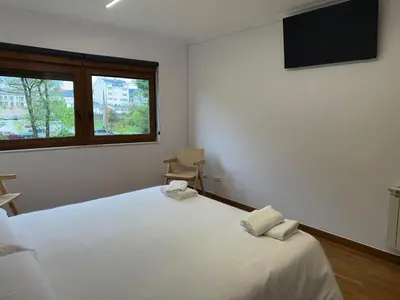 a bedroom with a large white bed and a window at Pensión Río Sarria in Sarria