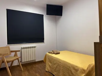 a room with a bed and a flat screen tv at Pensión Río Sarria in Sarria