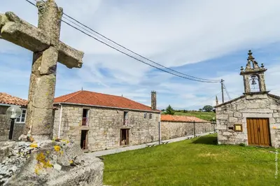 an old stone church with a cross and a tower at Casa do Ferrador in Penasillás