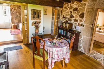 a dining room with a table and a stone wall at Casa do Ferrador in Penasillás