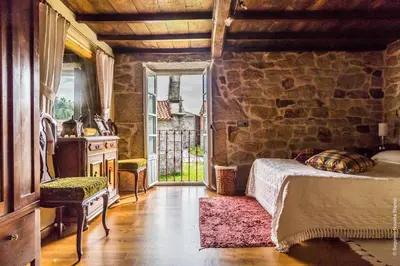 a bedroom with a bed and a stone wall at Casa do Ferrador in Penasillás