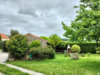 an old stone house in a green yard at Casa do Ferrador in Penasillás