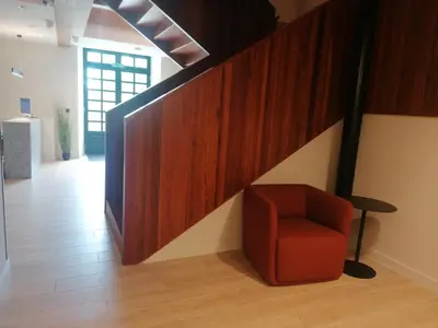 a red chair sitting under a staircase in a room at U-Hotel Aduana Ribadeo in Ribadeo