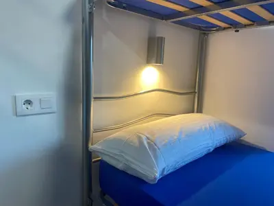 a bed in a small room with a light on it at Albergue o Bailarin in O Barco de Valdeorras