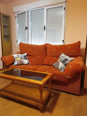 an orange couch in a living room with a coffee table at La Niña in Tineo