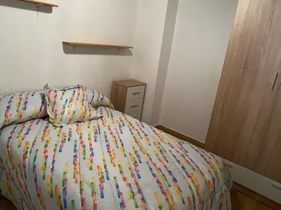 a bed with a colorful comforter in a bedroom at Casa centro histórico de Viveiro in Viveiro
