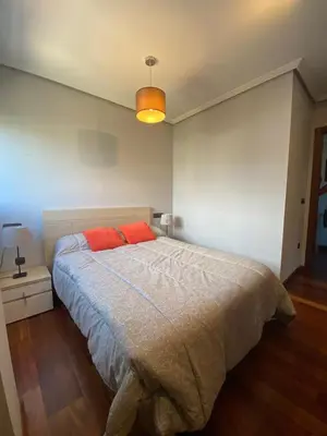 a bedroom with a large bed with a red pillow at Apartamento El Puerto in Puerto de Vega