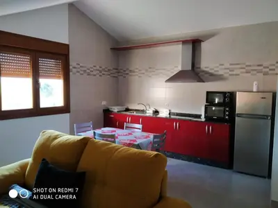 a living room with a couch and a kitchen with red cabinets at Casa Pura in Ribadeo