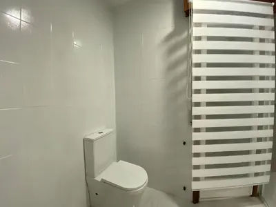 a bathroom with a toilet and a white wall at A un Paso in Caldas de Reis