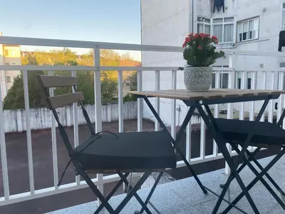 a table and chair on a balcony with a vase of flowers at A tres Pasos in Caldas de Reis