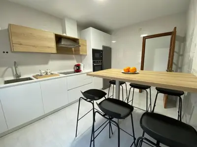a kitchen with white cabinets and a wooden counter with bar stools at La Huella de Caldas in Caldas de Reis