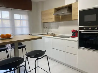 a kitchen with white cabinets and a counter with stools at La Huella de Caldas in Caldas de Reis