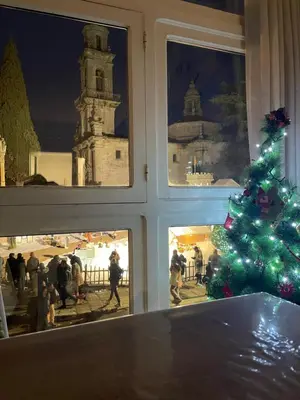a christmas tree in front of a window with people at Destino Allariz in Allariz