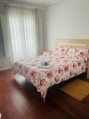 a bedroom with a bed with a flowered comforter with a clock on at Destino Allariz in Allariz