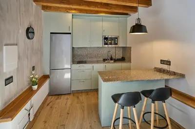 a kitchen with white cabinets and a counter with stools at O Campiño Alojamientos Turísticos in Trasmiras